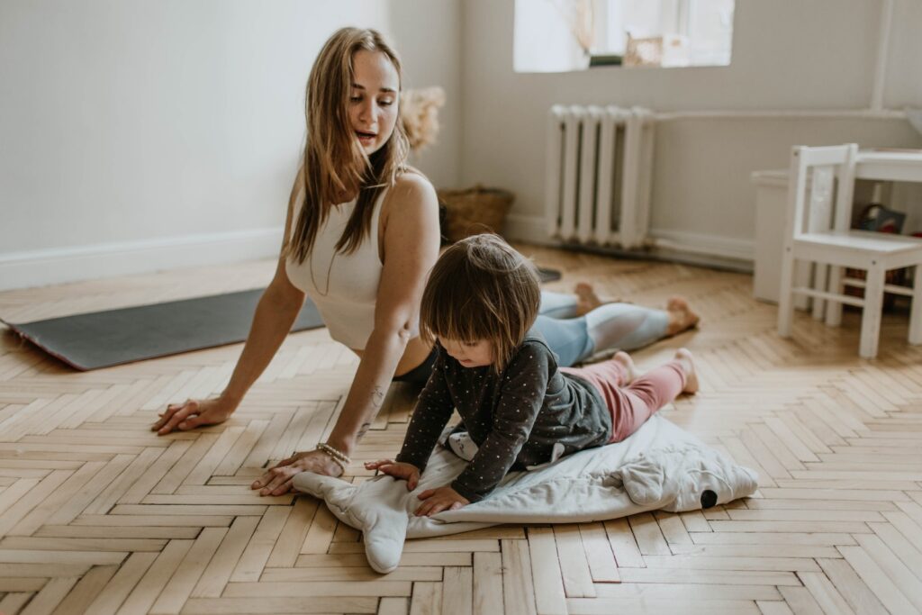 a young woman and her child stretch together on the floor