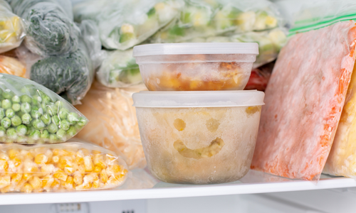 some ingredients stored in the freezer. Someone has drawn a smiley face in the frost on a container of frozen corn. 