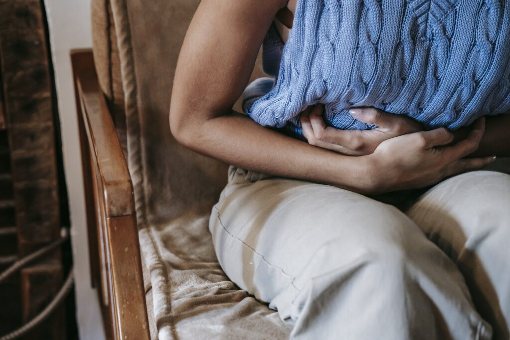 Crop unrecognizable female holding stomach while having period pain