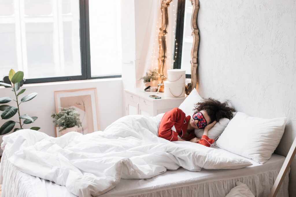 Woman Sleeping on a Bed in a bright room wearing a sleep mask