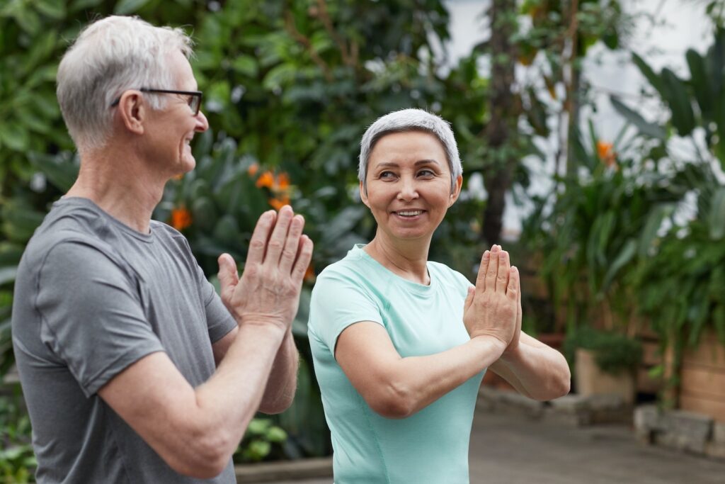 Couple Smiling While Looking at Each Other practicing yoga in a greenhouse 