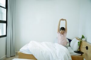 woman stretching arms above head sitting up in bed