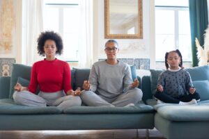 A Mother With Her Daughters Sitting On Sofa meditating cross legged