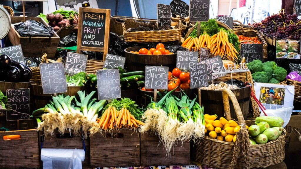 a farmers market stand featuring many colorful vegetables in wooden crates.