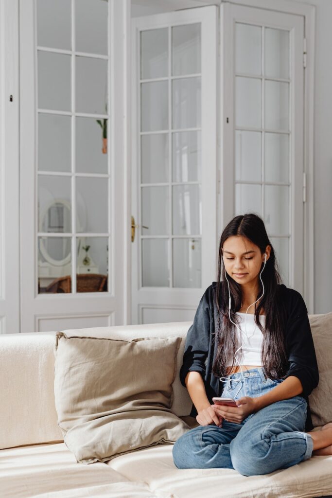 Woman Sitting on a Sofa while Listening to Music