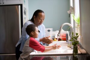 grandmother and grandson wash dishes together - she was adapting her home for chronic pain to make things easier