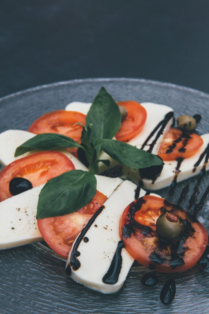 closeup photo of mozzarella, basil, and tomato slices covered in a drizzle of balsamic vinegar