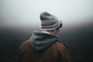 man wearing knit cap looking out into foggy grey background