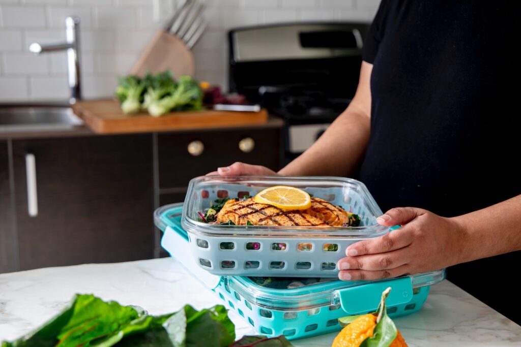 person holding a container with a meal that they will freeze