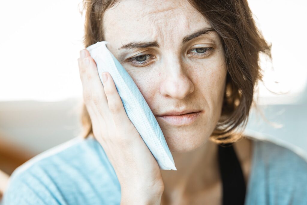 woman holding ice pack to face as part of cold therapy for chronic pain