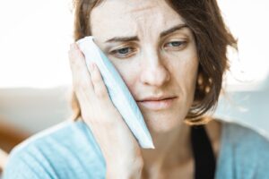 woman holding ice pack to face as part of cold therapy for chronic pain