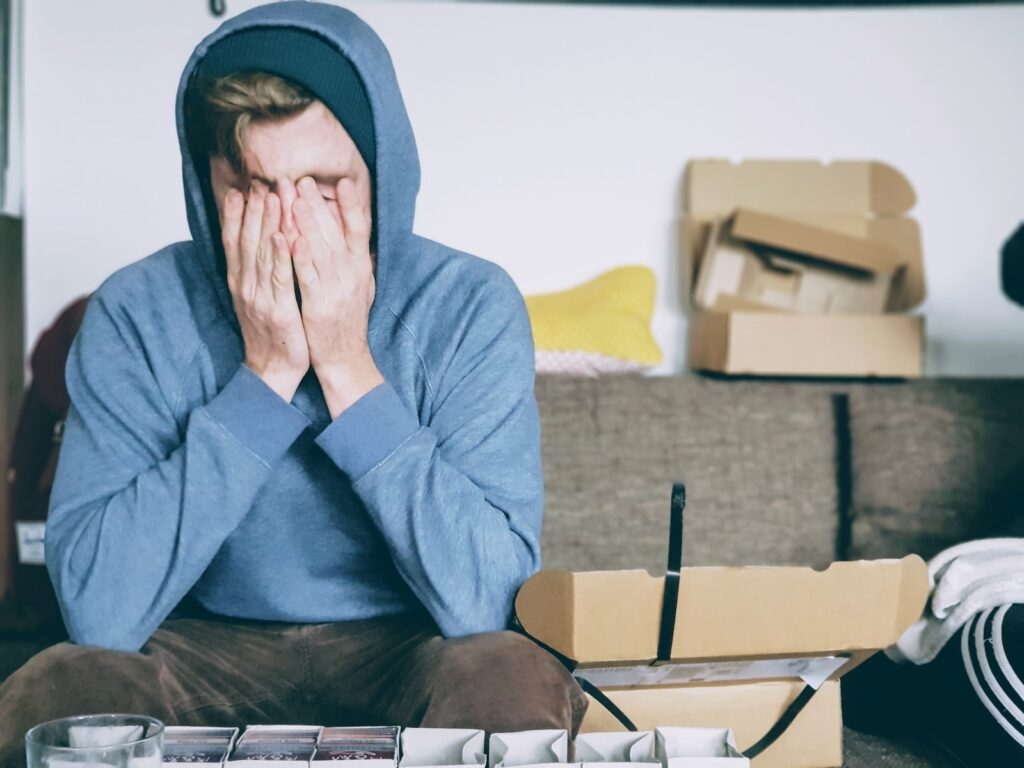 man covering face with both hands looking tired or upset while sitting on bench - he is experiencing brain fog