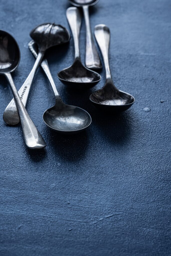 several silver spoons on a dark blue surface