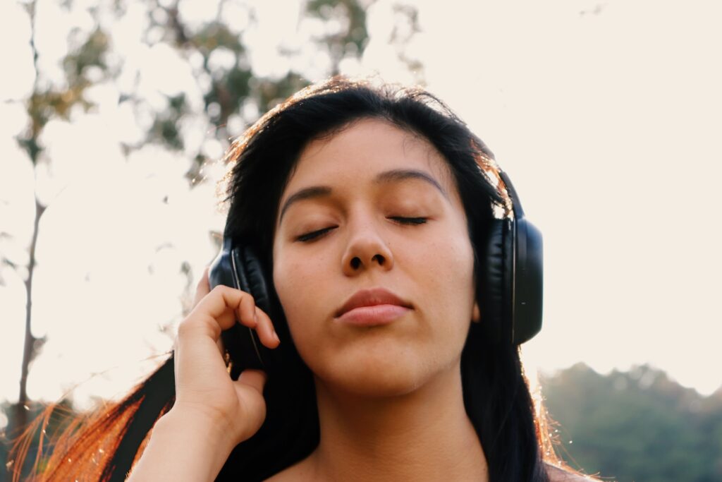 woman wearing black headphones and closing her eyes in enjoyment