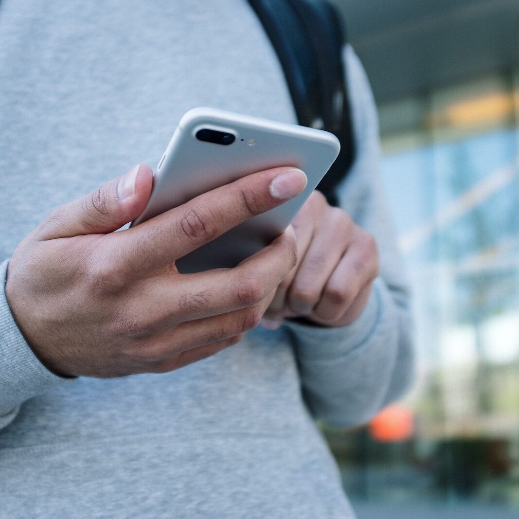 Person in Gray Long Sleeve Shirt Holding Silver Iphone 6